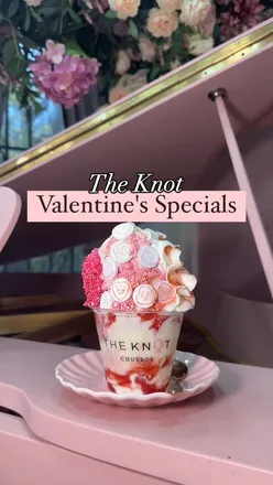 Pink hot chocolate with whipped cream, love heart candy, pink sparkles, and churros with pink chocolate at The Knot Churros.