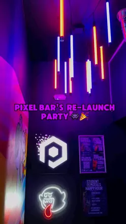 Group enjoying gaming-themed cocktails at Pixel Bar's re-launch party with upgraded booths and modern decor.