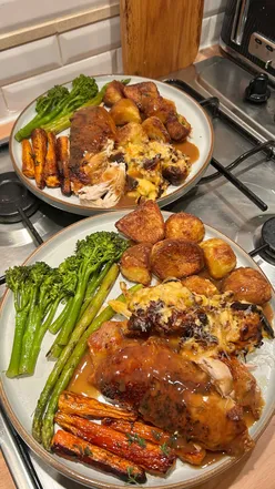 Delicious Sunday roast with chicken, roast potatoes, honey glazed carrots, cauliflower cheese, broccoli, asparagus, gravy.