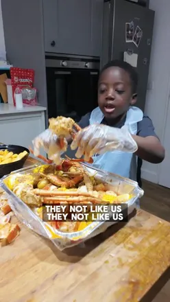 Father and son enjoying a seafood boil feast with crab, shrimp, and corn at a restaurant. #foodreview #seafood
