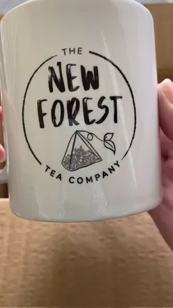 Ambassador box from New Forest Tea Co with assorted teas, a mug, and a card featuring art by Shaun Stevens.