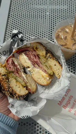 Cross section of an everything bagel with pastrami, honey mustard, cream cheese, and pickles in Melbourne.