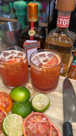 Two Hot Honey Blood Orange Margaritas with lime juice, Cointreau, and tajin rim, celebrating National Margarita Day.