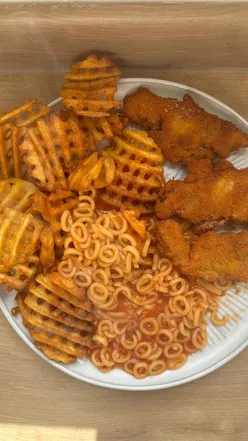Plate of turkey dinosaurs with chips and spaghetti hoops, evoking nostalgic school dinner memories.