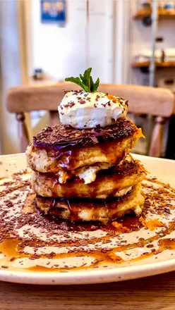 Tiramisu pancakes stack with orange zest at a Bath cafe, perfect for Pancake Day brunch. Fluffy, creamy, coffee delight.