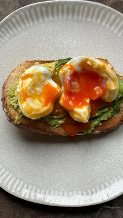 Avocado toast on sourdough topped with a soft boiled egg, perfect for a quick, healthy breakfast.