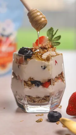 Layered granola bowl with Greek yogurt, fresh strawberries, blueberries, and Lizi's Granola for a quick breakfast.