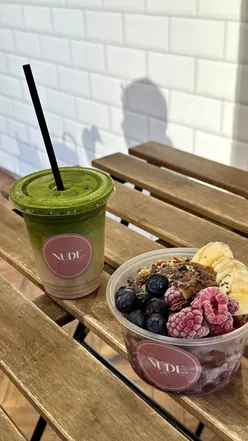 Bowl of açai topped with fresh berries and coconut, next to a matcha latte at Nudel Liverpool café.