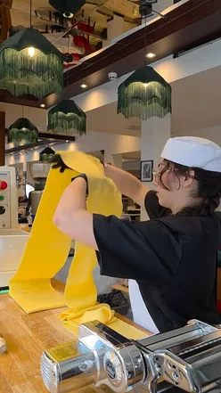 Chef rolling fresh Pappardelle pasta in a cozy kitchen, preparing for a busy day at Italian restaurant in Manchester.