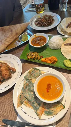 A vibrant Malaysian feast featuring cheese and spinach roti, mutton curry, and banana roti dessert at Market Halls.