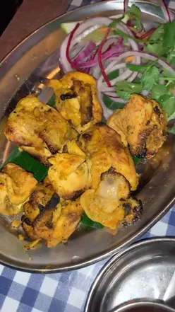 A vibrant spread of Dishoom dishes: crispy lamb samosas, chicken tikka, mutton pepper fry, garlic rice, and naan.