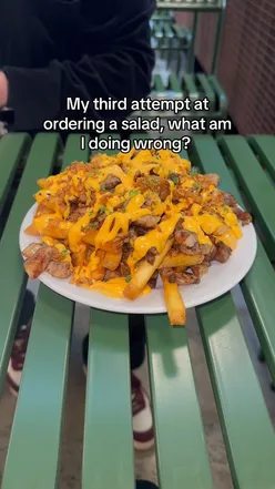Close-up of loaded fries topped with cheese, bacon, and green onions on a plate. #fries #loadedfries #food