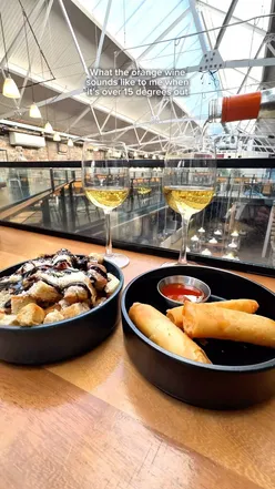 Delicious focaccia bites and veggie spring rolls with orange wine at Duke Street Market, perfect for sharing.