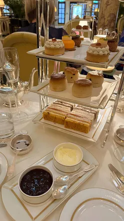 Luxurious afternoon tea at The Ritz with finger sandwiches, cakes, scones, and champagne in an opulent setting.