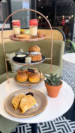 Afternoon tea with Scouse sausage rolls, Strawberry Fields macarons, and themed treats in Liverpool's garden room.