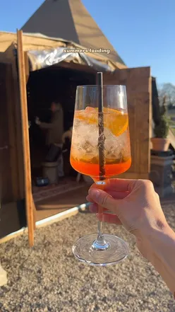 Enjoying alfresco Hugo spritz and fresh chorizo pizza at Tempus Tipi, Charlton Hall, with fairy lights and live music.
