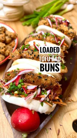 Crispy loaded tofu bao buns topped with rainbow slaw, radish, and chili for a vibrant vegan dish.