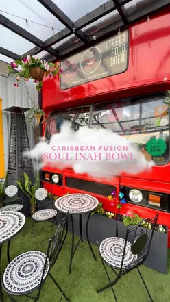Dinner on a double decker bus at Soul Inah Bowl, featuring halal Caribbean brown stewed chicken and vibrant seating.