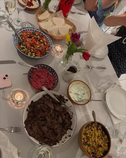 Engagement celebration meal with pomegranate lamb, hummus, tzatziki, coleslaw, Israeli salad, couscous, and bao buns.