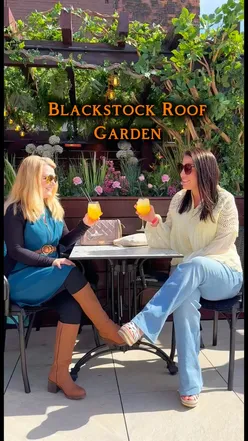 Cocktails on a sunny rooftop at Blackstock Roof Garden, Liverpool, with vibrant decor, live music, and diverse food options.