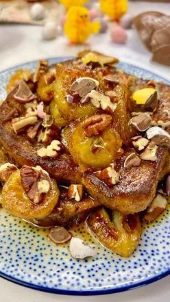 Easter French toast topped with caramelised bananas, toasted pecans, and chocolate, served on a plate.