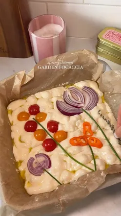 Homemade spring-themed focaccia with flower designs made from chives, tomatoes, and peppers for Easter.