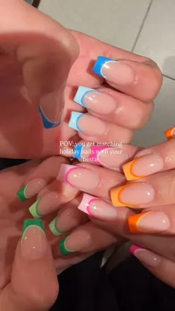 Two identical twins show off matching holiday nail designs, celebrating their festive spirit in Australia.