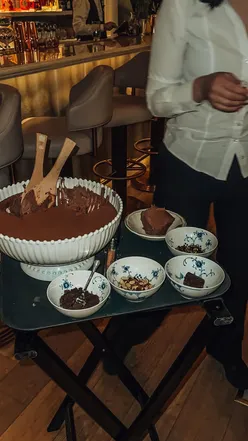Decadent chocolate mousse served tableside at Amélie restaurant in London, topped with customizable options.