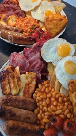 A delicious full English breakfast featuring fried eggs, crispy bacon, sausages, and golden hash browns.
