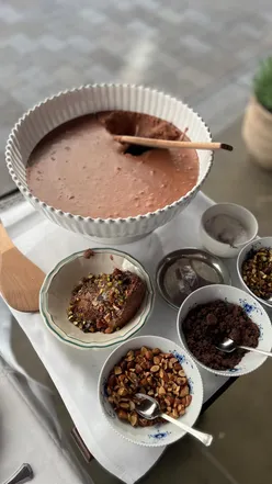 Indulgent homemade chocolate mousse with pistachio, almonds, and olive oil drizzle at Amélie restaurant.