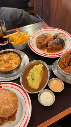 Delicious Coqfighter meal featuring roast chicken, spicy Stinger burger, cheesy corn, and fries in Kings Cross.