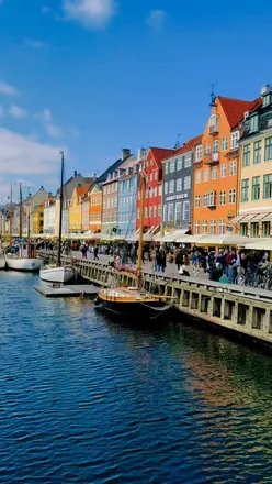 Colorful Nyhavn harbor in Copenhagen, showcasing vibrant buildings and people enjoying food and drinks by the water.