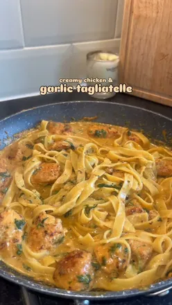 Creamy chicken and garlic tagliatelle with spinach, topped with reduced fat cheese, served in a bowl.