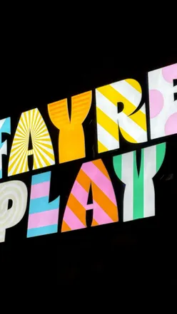 Group enjoying fun fair games at Fayre Play in Edinburgh with drinks and a lively atmosphere.