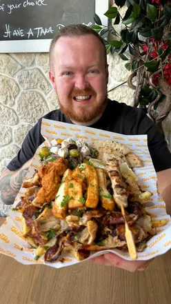 Massive Greek platter with chicken, salad, pita, and fries at Taka Bristol, showcasing delicious Mediterranean cuisine.