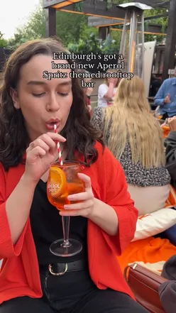 Aperol cocktails on a summer rooftop terrace with views of Edinburgh Castle and stylish decor.