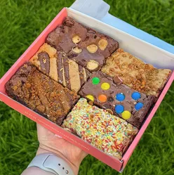 Assorted brownies and blondies from Gimmie Brownies' Mix Box, featuring Nutella, Birthday Cake, Honeycomb, Lotus Biscoff, M&M, and Double Chocolate flavors.