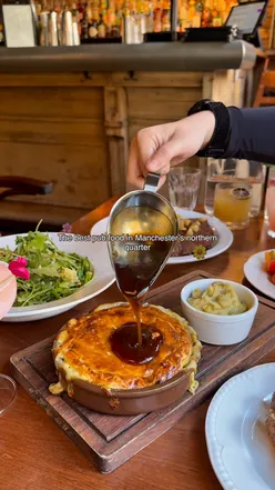 Cheesy leek and potato pie with gravy, perfectly cooked steak, heritage tomatoes, couscous salad, pork fennel sausages at Trof NQ, Manchester.