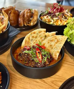 Teriyaki chicken burger with Korean fries, braised beef cheek, Korean chicken, wonton nachos, Goma Caesar, miso caramel espresso martini, and jungle mai tai at One O’clock Gate, Asian fusion restaurant in Dinas Powys.
