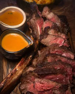 Porterhouse steak in Midlands, sliced with sea salt, served with blue cheese sauce, peppercorn, mac and cheese, dauphinois potatoes.