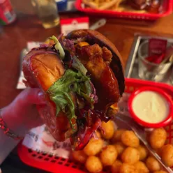 Girl enjoying Tipsy Texan with chicken tenders, cheese, BBQ sauce, slaw, tater tots, ranch, mac and cheese at Maggie's Rock N Rodeo in Glasgow.