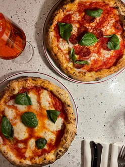 Classic margarita and Teresa pizza with sausage and chili at Giolina Milano, paired with tiramisu, torta caprese, and Aperol Spritz.