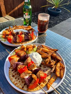Greek platter with chicken souvlaki, sweet chili halloumi, homemade wedges, flatbread, and tzatziki for alfresco dining.