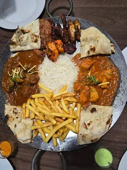 Desi tawa platter at An Najeeb Leicester with kebab, wings, lamb chops, chicken curry, naan, rice, and chips.