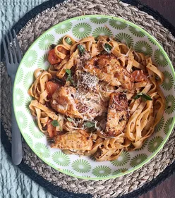 Homemade tagliatelle pasta with chicken, mushrooms, tomatoes, garlic, tomato paste, cheese, fresh basil, and oregano.