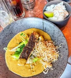 Crispy curried fish with coconut curry sauce, snap peas, samphire, crispy noodles, and jasmine rice at The Alchemist, Salford Quays.