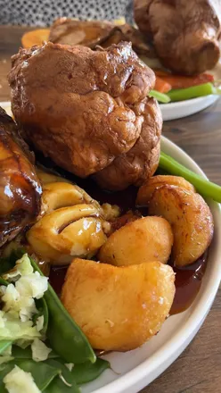 Tender lamb shank with roasted vegetables and gravy at The Potting Shed Bistro, a bright, floral North East dining spot.