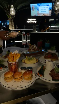 Argeela Digbeth's new menu: beef nachos, samosa chaat, wagyu sliders, chicken biryani, lamb steak, chicken fries, Malibu, tropical punch, non-alcoholic champagne in a dark, aesthetic setting.