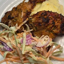 Tandoori lamb chops with mash and coleslaw, seasoned with yogurt, garlic, ginger, cumin, coriander, paprika, garam masala.