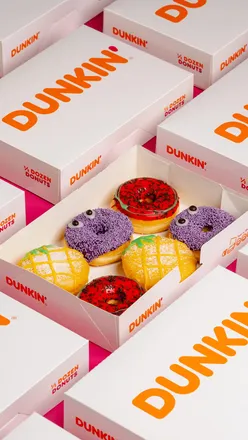 Vibrant Dunkin Donuts summer drinks on orange table with sky backdrop; doughnut tear adds texture and taste appeal.
